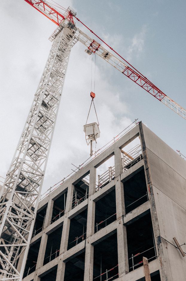 Grúa torre levantando materiales en la construcción de un edificio de hormigón