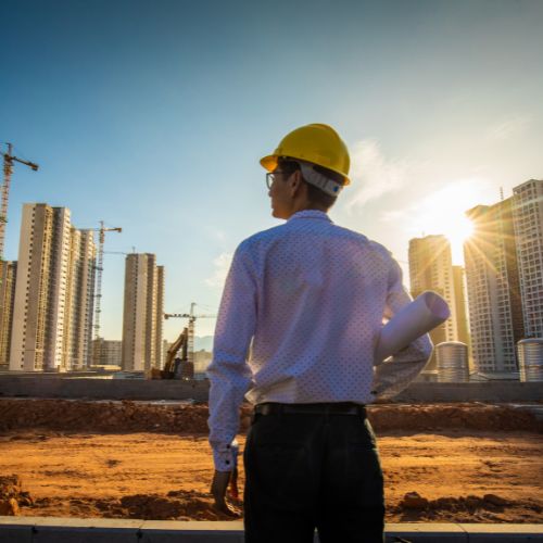 Ingeniero con casco observando obra urbana al atardecer